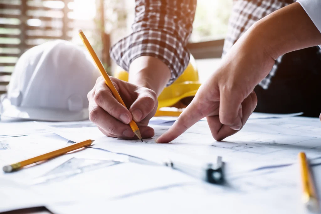 Comprehensive Bathroom Remodeling Contractors Oasis Bathroom Boca Raton Hands of bathroom remodeling contractors reviewing blueprints and planning renovation details, with construction tools and a hard hat visible, emphasizing professional collaboration in bathroom design.