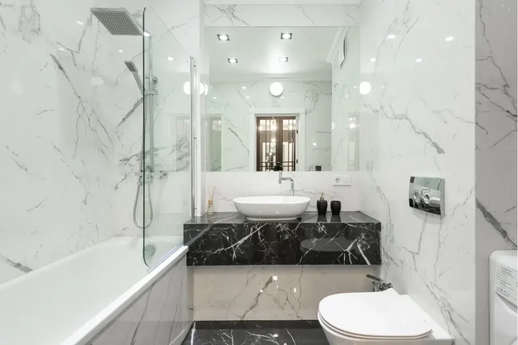 Expert Simple Modern Tub to Shower Conversion Oasis Bathroom Boca Raton Modern bathroom featuring a sleek tub-to-shower conversion with glass enclosure, marble walls, and stylish black and white accents, illustrating efficient space utilization and aesthetic appeal.