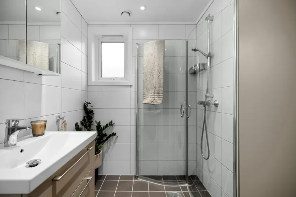 Modern small bathroom featuring a sleek shower enclosure, stylish sink with wooden cabinetry, and contemporary fixtures, emphasizing functionality and aesthetic appeal for a bathroom remodel.