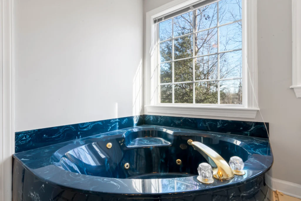 Jacuzzi Bathroom Remodel Oasis Bathroom Boca Raton Luxury jacuzzi bathtub with gold fixtures and blue marble surround, positioned near a large window for natural light, showcasing high-end bathroom remodel aesthetics.