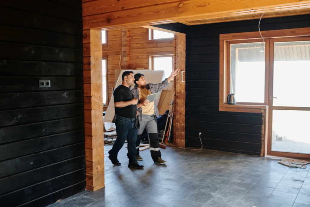 Planning Bathroom Remodeling Contractors Oasis Bathroom Boca Raton Two men discussing bathroom remodeling plans in a partially renovated space, showcasing wooden beams and large windows, emphasizing collaboration and design consultation.