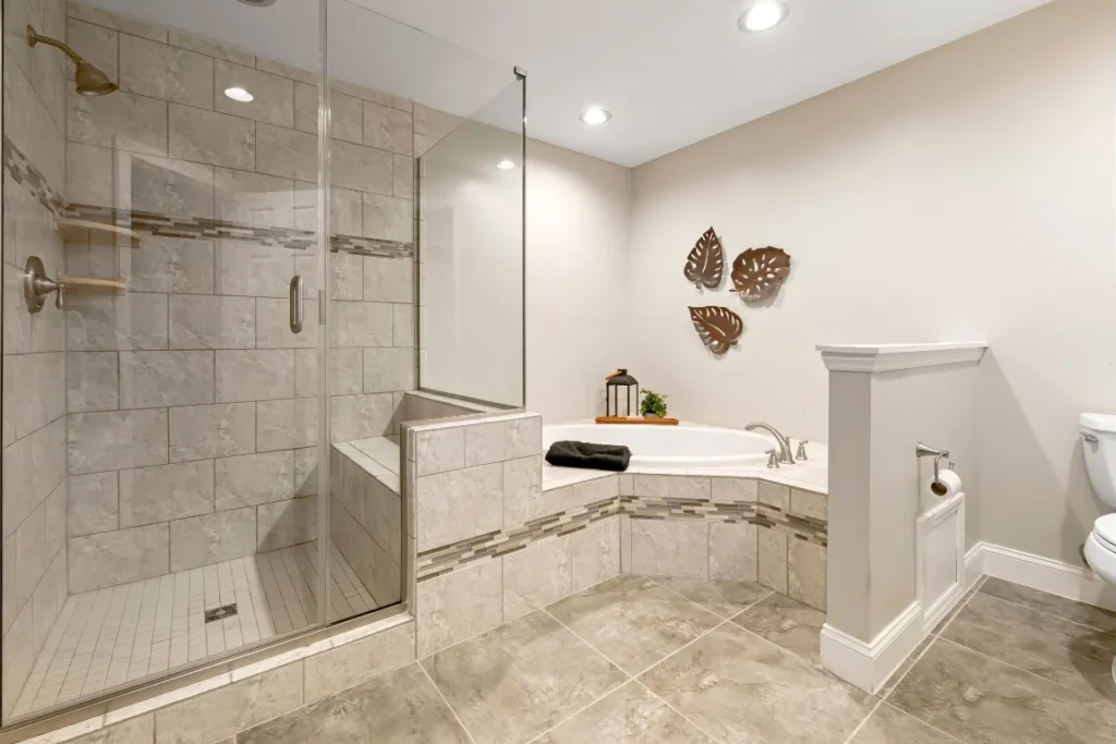 Modern bathroom with a spacious walk-in shower featuring glass doors, built-in seating, and elegant tilework, complemented by a freestanding bathtub and decorative elements, showcasing luxury and functionality for shower remodeling.