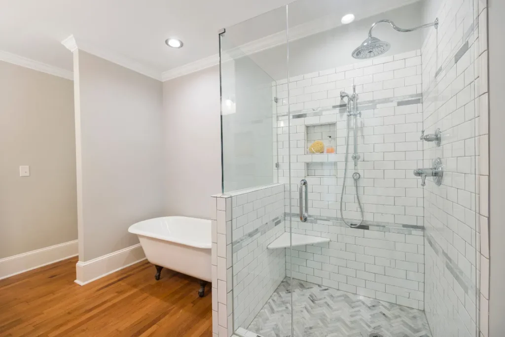 Modern glass shower enclosure with sleek white tiles and a freestanding bathtub in a renovated bathroom, showcasing stylish design and functionality for a shower remodel in Boca Raton.