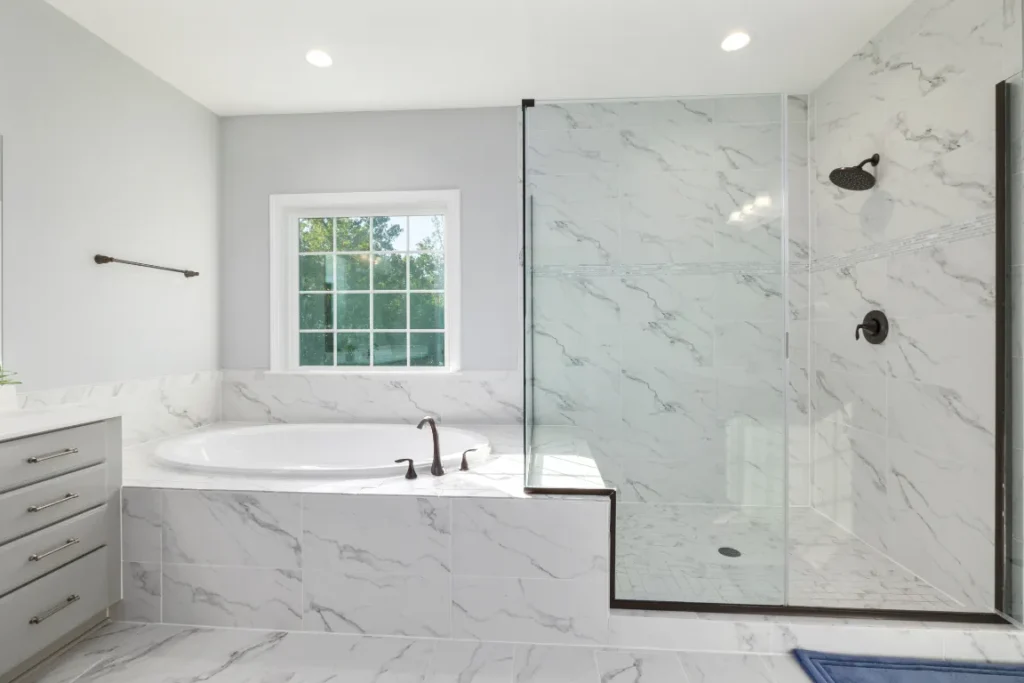 Modern bathroom featuring a seamless glass shower enclosure, a spacious white soaking tub, and elegant marble tiles, highlighting Oasis Bathroom Remodeling's expertise in stylish and functional shower renovations.