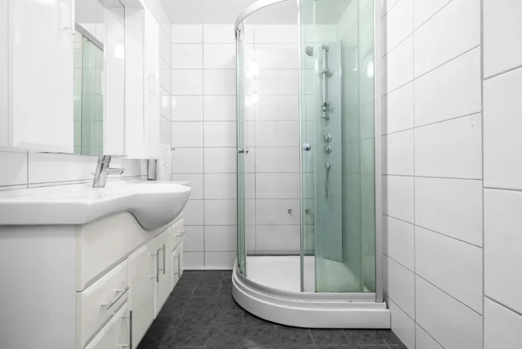 White Shower Remodel Oasis Bathroom Boca Raton Modern bathroom featuring a sleek glass shower enclosure, white tiled walls, and a contemporary vanity, illustrating a stylish shower remodel by Oasis Bathroom Remodeling in Boca Raton.